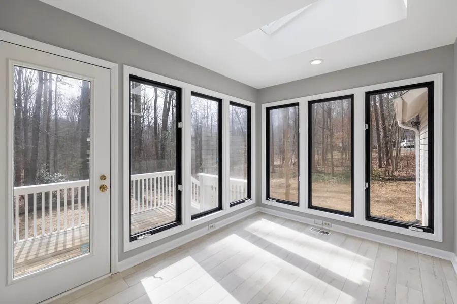A bright new room addition with walls of black-framed windows and pale tile floors