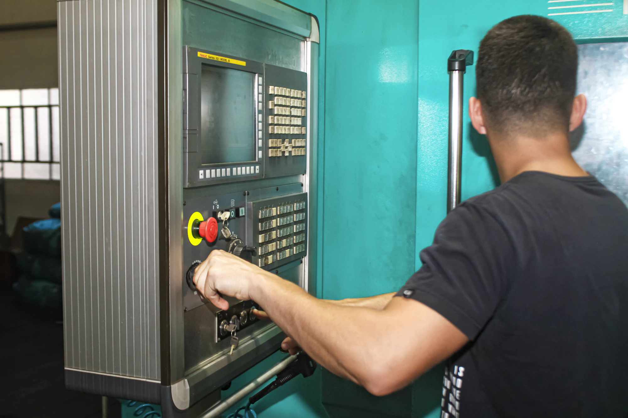 Machinist working the control panel of a CNC machining center