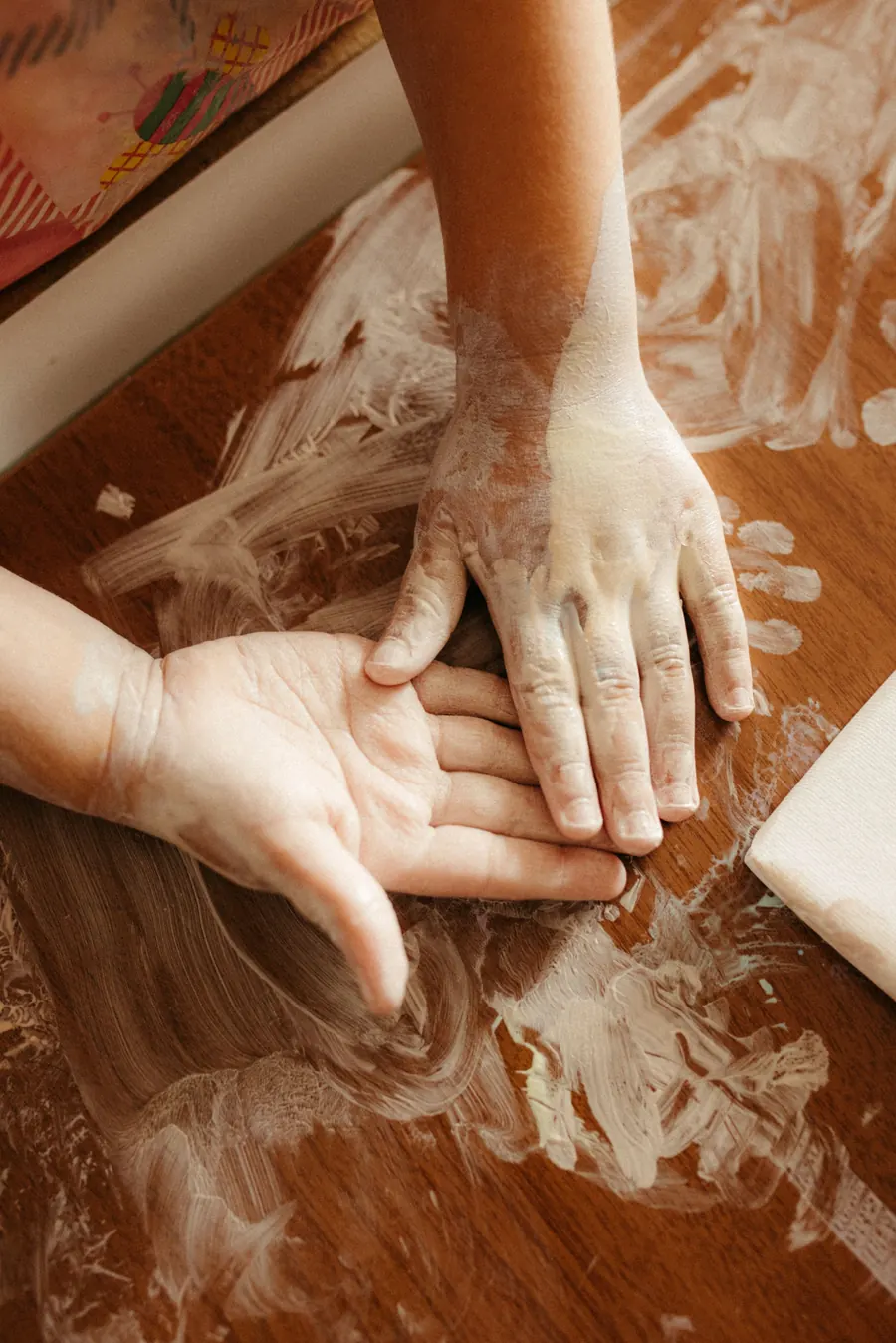 Children's hands finger painting on a wooden table